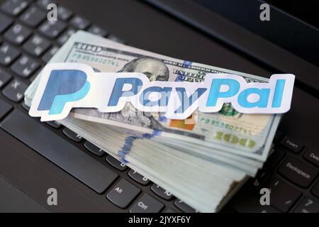 TERNOPIL, UKRAINE - 6. SEPTEMBER 2022 das Paypal-Papierlogo liegt auf einer schwarzen Laptop-Tastatur mit US-Dollar-Scheinen. Payoneer ist ein amerikanischer Finanzdienstleister Stockfoto