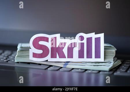 TERNOPIL, UKRAINE - 6. SEPTEMBER 2022 das Skrill-Papierlogo liegt auf einer schwarzen Laptop-Tastatur mit US-Dollar-Scheinen. Payoneer ist ein amerikanischer Finanzdienstleister Stockfoto