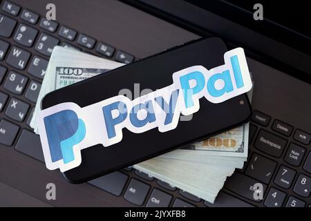 TERNOPIL, UKRAINE - 6. SEPTEMBER 2022 das Paypal-Papierlogo liegt auf einer schwarzen Laptop-Tastatur mit US-Dollar-Scheinen. Payoneer ist ein amerikanischer Finanzdienstleister Stockfoto