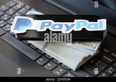 TERNOPIL, UKRAINE - 6. SEPTEMBER 2022 das Paypal-Papierlogo liegt auf einer schwarzen Laptop-Tastatur mit US-Dollar-Scheinen. Payoneer ist ein amerikanischer Finanzdienstleister Stockfoto