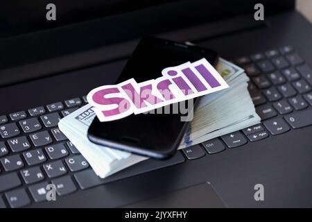 TERNOPIL, UKRAINE - 6. SEPTEMBER 2022 das Skrill-Papierlogo liegt auf einer schwarzen Laptop-Tastatur mit US-Dollar-Scheinen. Payoneer ist ein amerikanischer Finanzdienstleister Stockfoto