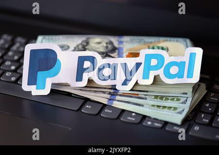 TERNOPIL, UKRAINE - 6. SEPTEMBER 2022 das Paypal-Papierlogo liegt auf einer schwarzen Laptop-Tastatur mit US-Dollar-Scheinen. Payoneer ist ein amerikanischer Finanzdienstleister Stockfoto