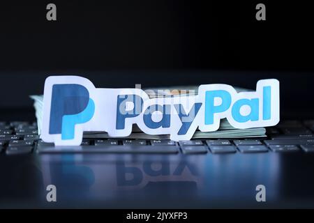 TERNOPIL, UKRAINE - 6. SEPTEMBER 2022 das Paypal-Papierlogo liegt auf einer schwarzen Laptop-Tastatur mit US-Dollar-Scheinen. Payoneer ist ein amerikanischer Finanzdienstleister Stockfoto