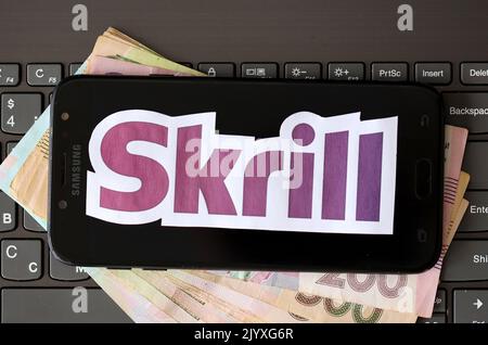 TERNOPIL, UKRAINE - 6. SEPTEMBER 2022 das Skrill-Papierlogo liegt auf einer schwarzen Laptop-Tastatur mit ukrainischen Griwna-Rechnungen. Payoneer ist ein amerikanischer Finanzdienstleister Stockfoto