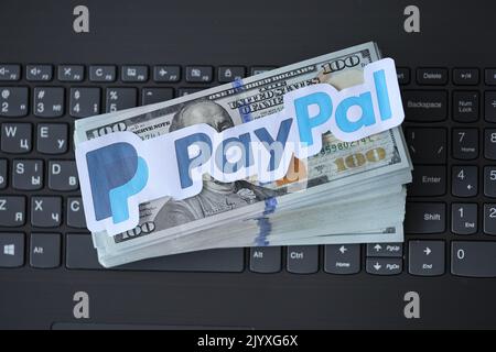 TERNOPIL, UKRAINE - 6. SEPTEMBER 2022 das Paypal-Papierlogo liegt auf einer schwarzen Laptop-Tastatur mit US-Dollar-Scheinen. Payoneer ist ein amerikanischer Finanzdienstleister Stockfoto