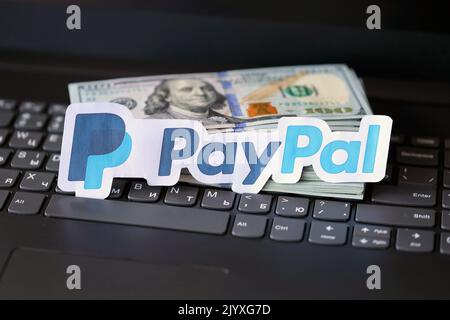 TERNOPIL, UKRAINE - 6. SEPTEMBER 2022 das Paypal-Papierlogo liegt auf einer schwarzen Laptop-Tastatur mit US-Dollar-Scheinen. Payoneer ist ein amerikanischer Finanzdienstleister Stockfoto