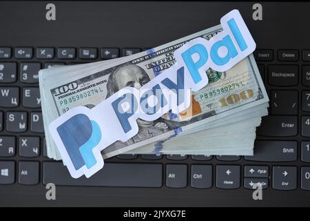 TERNOPIL, UKRAINE - 6. SEPTEMBER 2022 das Paypal-Papierlogo liegt auf einer schwarzen Laptop-Tastatur mit US-Dollar-Scheinen. Payoneer ist ein amerikanischer Finanzdienstleister Stockfoto