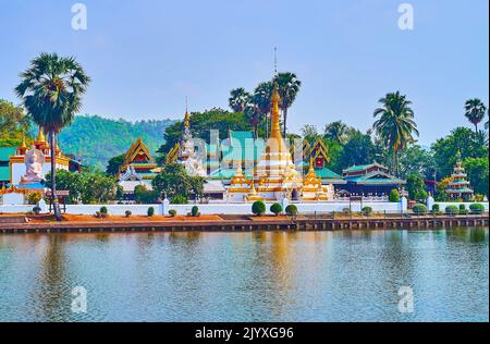 Die hti-Schirme, Chedi und Türme des Wat Chong Klang Temple, umgeben von einem tropischen Garten vor dem Nong Kham Lake, Mae Hong Son, Thailand Stockfoto
