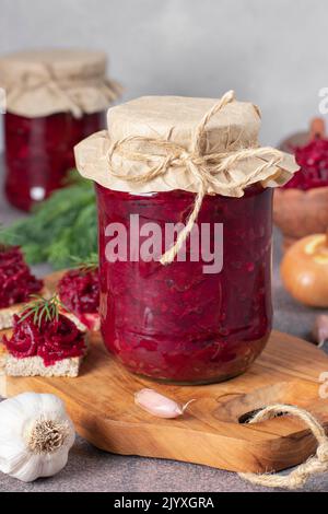 Hausgemachter würziger Kaviar aus Rüben, Karotten, Zwiebeln und Knoblauch in zwei Gläsern auf Holzbrett Stockfoto