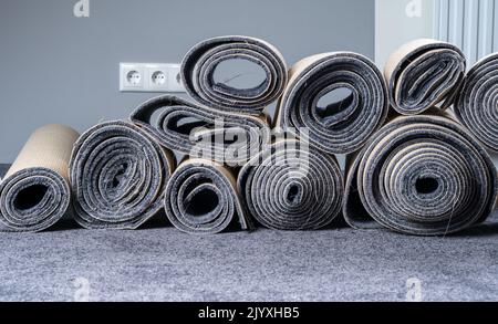 Alte Teppichrollen in einem grauen Raum gestapelt. Stockfoto