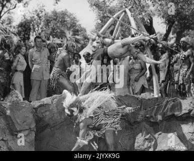 Gordon (Tarzan) Scott und Witch Doctor Jester Harrison werden von Kriegern aus Sukulu in die Löwengrube geworfen, während das Medical Team der Vereinten Nationen, bestehend aus Peter Van Eyck und Vera Miles, in einer Szene aus „Tarzan's Hidden Jungle“, die von Sol Lesser produziert und von RKO Radio vertrieben wird, an die Reihe kommt. 14. Oktober 1955. Stockfoto