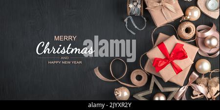 Weihnachtshintergrund mit Geschenkschachteln und Spielzeug auf schwarzem Hintergrund. Stockfoto