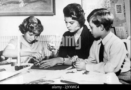 Schwedische Königskinder bereiten ihre Weihnachtsgeschenke vor. Wie jede andere Familie sind auch die Königskinder Schwedens beschäftigt - Kronprinz Carl Gustaf (rechts) beobachtet seine Schwester Prinzessin Christina (links) im Alter von 12 Jahren und Prinzessin Hargaretha (21) im königlichen Schloss in Stockholm. 22. Dezember 1955. (Foto von AP Wirephoto) Stockfoto