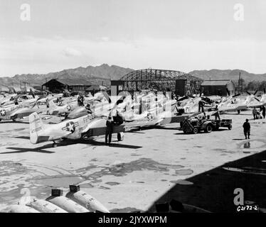 Re - Readying Operations Begin -- Wenn die US Air Force F - 51 Mustangs des Veteranen 18. Fighter Bomber Wing von einem Kampfangriff auf kommunistische Ziele in Nordkorea zurückkehrt, bilden sie sich in eine "Follow-the-Leader"-Reihe, wie oben gezeigt, um die Effizienz beim Nachladen von Patronen und bei den Wiederaufrüstung zu erhöhen. Der Tankwagen ist vorne beschäftigt, da die Besatzung lädt. 50 Kaliber-Munitionskaliber in Flügelfächer des Mustang rechts. Bald Raketen- und Bombenanhänger, die Anhänger tragen, werden sich durch die Reihen der Kämpfer - Bomber führen. Die Hochgeschwindigkeitsraketen werden geladen, während sie jedes Flugzeug passieren. Napalm Tanks sind Stockfoto