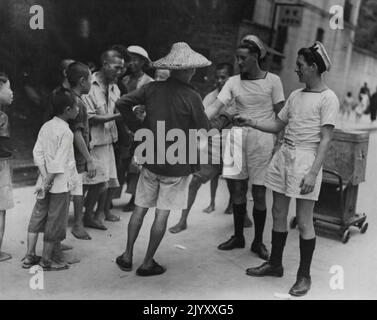 Britische Matrosen kehren in die Friedenszeit als Botschafter guten Willens zurück. A/B F.B. Simpson aus Darlington und A/B B. Millan aus Manchester schließen sich in Hongkong mit chinesischen Kindern an. Sie dienen auf HM Cruiser Euryalus, einem der britischen Kriegsschiffe, die die Wiederbesetzung der Kronkolonie beeinflussten. 18. September 1945. (Foto vom offiziellen Foto der Royal Naval). Stockfoto
