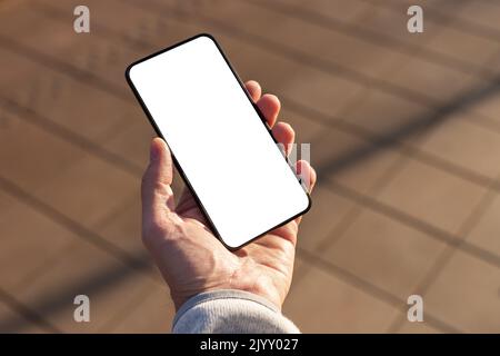 Hand hält das Handy-Modell auf dem Straßenbelag. Mobile App für das Stadtleben. Anwendung für die Suche nach Anwendung, Lebensmittel, Veranstaltungen, Gehäuse. Smartphone-Tem Stockfoto