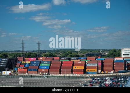 Southampton, England, Großbritannien - 7. Juli 2022: Hafenlandschaft. Dock mit gestapelten Containern aller Herkunft. Parkplatz vor dem Hotel unter blauer Wolkenlandschaft und g Stockfoto