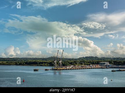 Southampton, England, Großbritannien - 7. Juli 2022: Hafenlandschaft. Weitblick auf 2 Eisenbahnpiers am Südufer des River Test unter blauer Wolkenlandschaft. Grüner Gürtel w Stockfoto