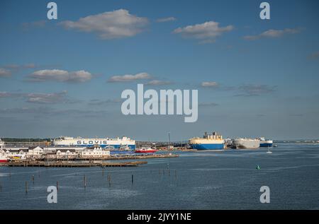 Southampton, England, Großbritannien - 7. Juli 2022: Hafenlandschaft. Mehrere große Autoträgerschiffe an Docks am südöstlichen Ende des Hafens unter blauer Wolkenlandschaft. Stockfoto