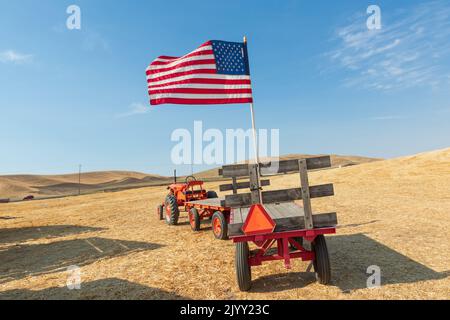 USA, Washington State, Palouse Empire Fairgrounds, Whitman County. Traktor und amerikanische Flagge. Stockfoto