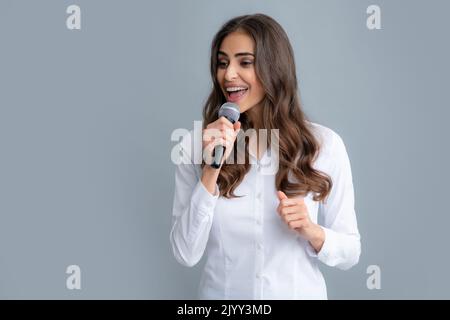 Frauenrede, Geschäftsfrau mit Mikrofon. Porträt einer jungen Journalistin in einem legeren Hemd mit Mikrofon, Fragen stellen, diskutieren Stockfoto