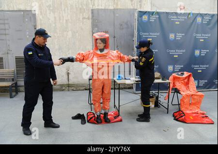 Lviv, Ukraine. 08. September 2022. Rettungskräfte des ukrainischen Notministeriums helfen einer Frau, während einer nuklearen Notfallschulung für Zivilisten Schutzkleidung anzuziehen. Kiew forderte am 7. September die Einrichtung einer internationalen Mission im Kernkraftwerk Saporischschschja und forderte die Bevölkerung auf, das Gebiet inmitten der Angst vor einer nuklearen Katastrophe zu evakuieren. (Foto von Mykola Tys/SOPA Images/Sipa USA) Quelle: SIPA USA/Alamy Live News Stockfoto