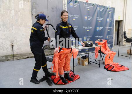 Lviv, Ukraine. 08. September 2022. Ein Rettungsassistent des ukrainischen Notministeriums hilft einer Frau, während einer nuklearen Notfallschulung für Zivilisten Schutzkleidung anzuziehen. Kiew forderte am 7. September die Einrichtung einer internationalen Mission im Kernkraftwerk Saporischschschja und forderte die Bevölkerung auf, das Gebiet inmitten der Angst vor einer nuklearen Katastrophe zu evakuieren. (Foto von Mykola Tys/SOPA Images/Sipa USA) Quelle: SIPA USA/Alamy Live News Stockfoto