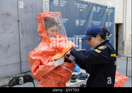 Lviv, Ukraine. 08. September 2022. Ein Rettungsassistent des ukrainischen Notministeriums hilft einer Frau, während einer nuklearen Notfallschulung für Zivilisten Schutzkleidung anzuziehen. Kiew forderte am 7. September die Einrichtung einer internationalen Mission im Kernkraftwerk Saporischschschja und forderte die Bevölkerung auf, das Gebiet inmitten der Angst vor einer nuklearen Katastrophe zu evakuieren. (Foto von Mykola Tys/SOPA Images/Sipa USA) Quelle: SIPA USA/Alamy Live News Stockfoto