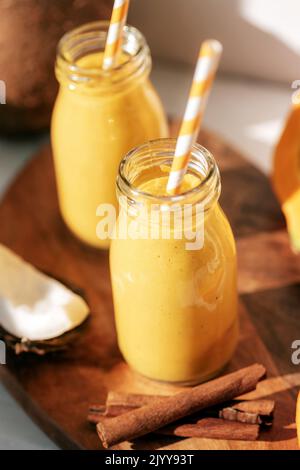 Kürbis und Kokosnuss-Smoothie mit Zimt in Flaschen mit Stroh. Gesundes, rohes veganes Essen. Nahaufnahme. Stockfoto