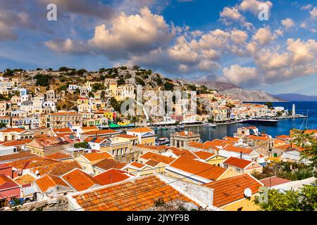 Blick auf die schöne griechische Insel Symi (Simi) mit bunten Häusern und kleinen Booten. Griechenland, Symi Insel, Blick auf die Stadt Symi (bei Rhodos), Stockfoto