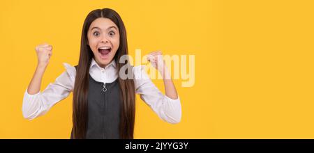 Glückliche Teenager-Mädchen Gewinner geben Gewinnergeste feiern Sieg gelben Hintergrund, gewonnen. Kindergesicht, horizontales Poster, Teenager-Mädchen isoliert Stockfoto