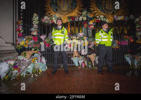 LONDON, ENGLAND - 08. SEPTEMBER: Polizeibeamte stehen unter floralen Ehrungen, die vor dem Buckingham Palace im Zentrum Londons nach der Ankündigung des Todes von Königin Elizabeth II. Hinterlassen wurden.Quelle: Horst A. Friedrichs Alamy Live News Stockfoto