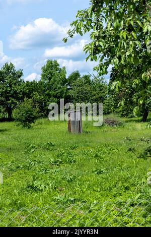 Eine Toilette, die auf dem Land im Garten installiert ist, eine primitive ländliche Holztoilette auf der Straße Stockfoto