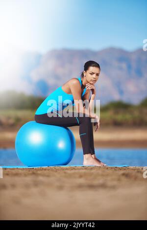 Wenn Sie abhängen können, können Sie trainieren. Eine junge Frau, die eine Pause auf ihrem Übungsball macht. Stockfoto