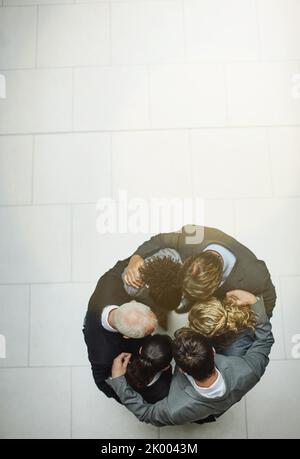 Der Tag begann mit einem Huddle. Aufnahme einer Gruppe von Geschäftsleuten, die in einem Gehege stehen. Stockfoto