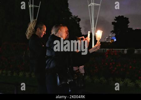 London, Großbritannien, 8.. September 2022. Drei Frauen fotografieren ihre Kerzen, die zur Erinnerung an Ihre Majestät, die Königin, angezündet werden, während Hunderte vor ihrem Londoner Wohnsitz, dem Buckingham Palace, ihren Respekt zollen, bis spät in den Abend, nachdem ihr Tod am frühen Abend angekündigt wurde. Das Land wird nun zehn Tage lang trauern, da die 70-jährige Regierungszeit des Monarchen zu Ende geht. Quelle: Elft Hour Photography/Alamy Live News Stockfoto