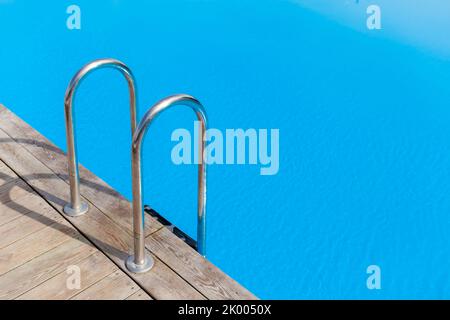 Leiter Edelstahlgeländer für den Abstieg in den Swimmingpool. Schwimmbad mit Geländer . Leiter des Schwimmbades. Die Leute schwimmen und entspannen sich im Pool Stockfoto