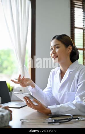 Porträt, Experte und schöne junge asiatische Ärztin trifft sich mit ihrer Patientin im Büro und gibt ihrem Patienten medizinische und chirurgische Ratschläge. Stockfoto