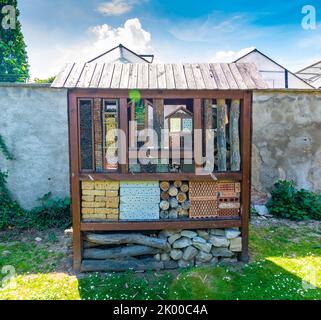 Insektenhotel. Holzhaus für Insekten, Insekten, Bienen. Dekoratives Tierheim, Konzept der ökologischen und naturfreundlichen Landwirtschaft. Sommerwetter, blau Stockfoto