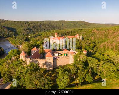 Luftaufnahme der Burg Veveri in der Nähe der Stadt Brünn. Region Südmähren, umgeben vom Fluss Svratka. Sommertag mit blauem Himmel, Sonnenuntergang und sanftem Licht. Stockfoto