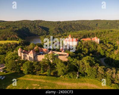 Luftaufnahme der Burg Veveri in der Nähe der Stadt Brünn. Region Südmähren, umgeben vom Fluss Svratka. Sommertag mit blauem Himmel, Sonnenuntergang und sanftem Licht. Stockfoto