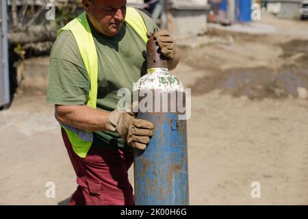 Bukarest, Rumänien - 8. September 2022: Details zur geringen Schärfentiefe (selektiver Fokus) bei einem Arbeiter, der einen industriellen Sauerstofftank umsetzt. Stockfoto