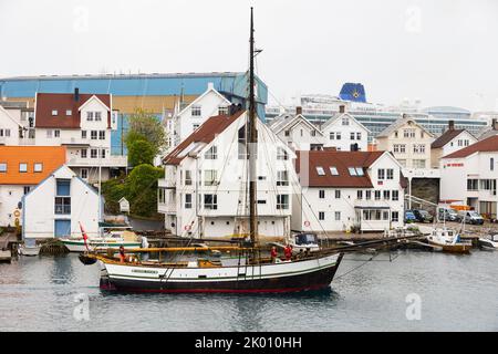 Restaurierte, historische Hardanger-Yacht, Johanne Karine, fährt aus dem Hafen von Haugesund. P&O-Kreuzschiff, Iona liegt im Hintergrund., Norwegen Stockfoto