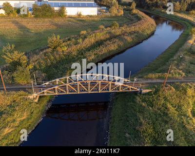 Alte Stahl-Straßenbahnbrücke über den Fluss Ner in der Stadt Lutomiersk, Polen. Stockfoto