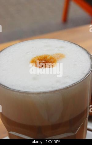 Glas Tasse Latte auf dem Holztisch. Französisches Frühstück im Macaronnerle Cafe in Heidelberg mit französischem Flair. Draufsicht. Nahaufnahme, Makro. Stockfoto