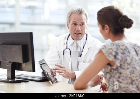 Dem Patienten alle Informationen geben, die er braucht. Arzt und Patient in einer Arztpraxis. Stockfoto