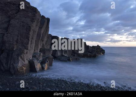 Vulkanische Gesteinsformationen an der Küste des Atlantischen Ozeans in der Abenddämmerung, Strand Praia Formosa in der Nähe von Funchal Madeira Portugal. Stockfoto