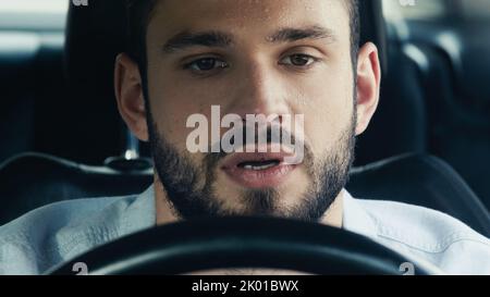 Junger bärtiger Mann mit verschwitzter Stirn, der bei heißem Wetter Auto fährt, Stockbild Stockfoto