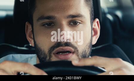 Porträt eines Mannes mit Schweiß auf der Stirn, der das Auto am heißen Sommertag fährt, Stockbild Stockfoto