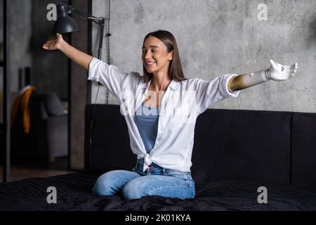 Portrait glückliche Frau mit prothetischen Arm, Mädchen mit Behinderung entspannend Anheben der Arme künstliche Prothese Extremität. Stockfoto